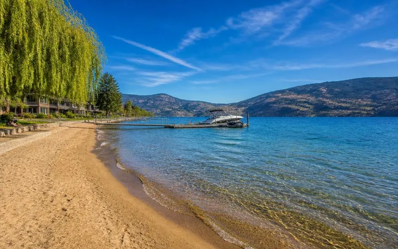 Sandy beach and clear turquoise water at Okanagan Landing in Vernon, BC with mountain views